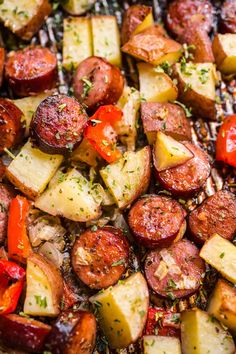 cooked sausages, potatoes and peppers on a grill with herbs sprinkled on top