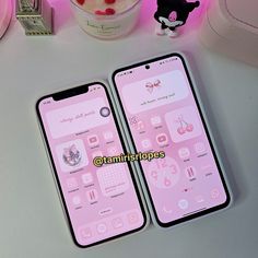 two pink iphones sitting next to each other on a white table with candy in the background