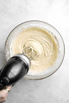 someone mixing batter in a bowl with a hand mixer