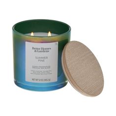 a candle that is sitting next to a wooden lid on a white background with the words, better homes & gardens summer pine