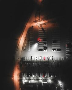 an aerial view of a parking lot at night with cars parked on the street below