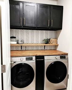 a washer and dryer in a small room with black cabinetry on the wall