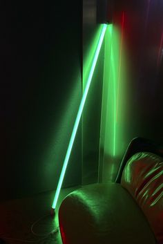 a green light is shining on the wall next to a white couch in a dark room