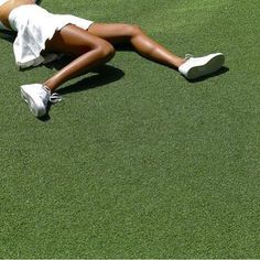 a woman laying on top of a lush green field next to a white frisbee