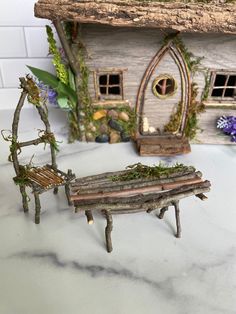 two miniature wooden benches sitting next to each other on a white counter top in front of a doll house