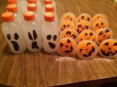 plastic bottles filled with orange candles sitting on top of a wooden table next to halloween decorations