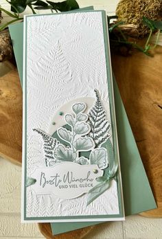 a close up of a card on a wooden table with flowers and leaves in the background