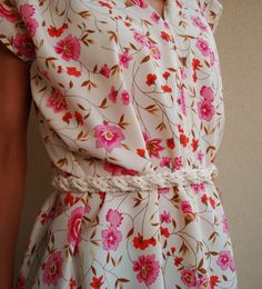 a woman is wearing a floral dress with braids on the waist and pink flowers on it