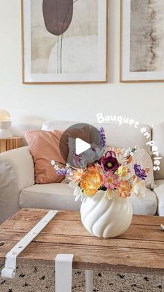 a living room filled with furniture and flowers on top of a wooden table in front of a white couch