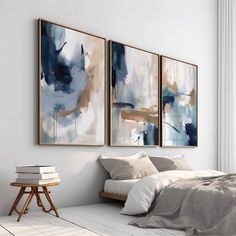 two paintings on the wall above a bed in a room with white walls and flooring