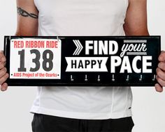 a man holding up a sign that says find your happy pace and red ribbon ride