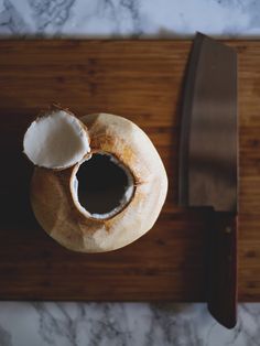 a wooden cutting board topped with an open coconut