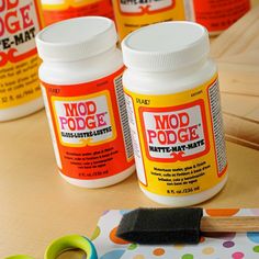 three bottles of mod podge paint sitting on top of a table next to scissors