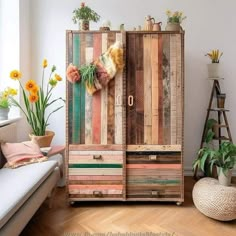 an old wooden cabinet is decorated with flowers and potted plants in the living room