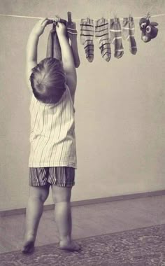 a little boy that is standing in front of a string with clothes hanging from it