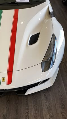 the front end of a white sports car with red, green and yellow stripes on it