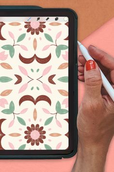 a woman's hand is holding a pen and drawing on an ipad with a flower pattern