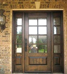 a large wooden door with glass on the side of a brick wall and stone steps