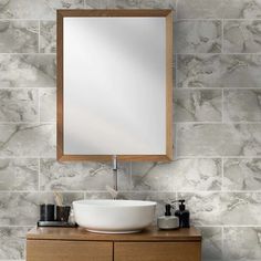 a bathroom sink sitting under a mirror next to a wooden cabinet and wall mounted faucet