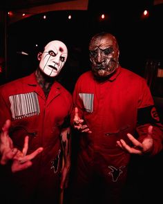 two men in red shirts with painted faces and hands are standing next to each other