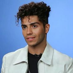 a man with curly hair wearing a white jacket