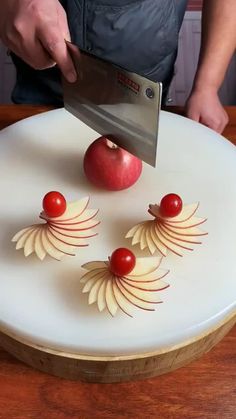 a person cutting an apple on top of a white plate with cherry tomatoes and leaves