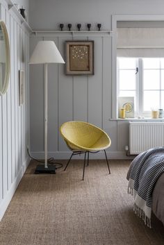 a yellow chair sitting on top of a bed in a bedroom next to a lamp