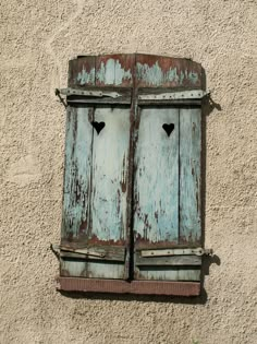 an old wooden window with two hearts on it's shutters, painted blue