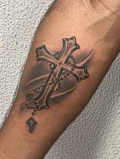 a man's arm with a cross and rosary tattoo on the left side of his arm