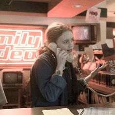 a woman sitting at a table talking on the phone