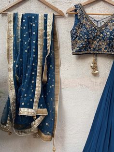 A three-piece teal blue embroidered lehenga set from the Priti Sahni collection. This beautiful georgette teal blue box pleated lehenga is paired with a sequin, and zardozi hand-embroidered blouse. The blouse has a ghungroo tassel tie-up at the back. And the lehenga has an embroidered belt to the waistline. This outfit is completed with a sequined work net dupatta. Blue Chanderi Pre-draped Saree With Intricate Embroidery, Blue Sets With Sheer Dupatta In Traditional Drape, Blue Traditional Drape Sets With Sheer Dupatta, Traditional Blue Sets With Sheer Dupatta, Blue Dola Silk Pre-draped Saree For Reception, Blue Sheer Dupatta Set For Navratri, Unstitched Blue Pre-draped Saree With Intricate Embroidery, Blue Georgette Choli For Transitional Season, Transitional Season Blue Anarkali Lehenga