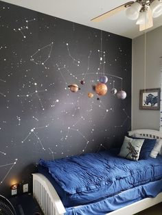 a bedroom with a space theme painted on the wall next to a bed and ceiling fan