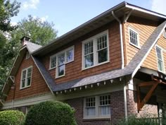 a brown house with white trim and windows on the side of it's roof