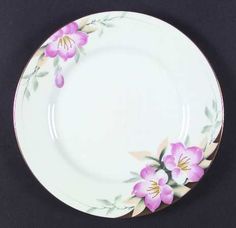 a white plate with pink flowers painted on the front and side, sitting on a black surface