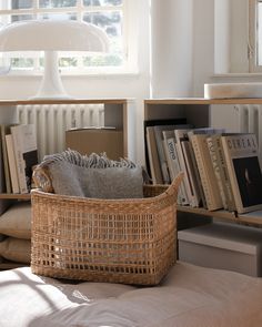 a wicker basket sitting on top of a bed in front of a book shelf