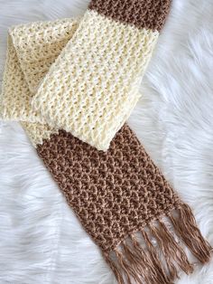 two crocheted scarves laying on top of a white furnishing area