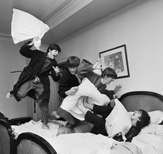 a group of people jumping in the air over a bed