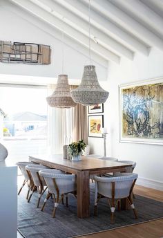 the dining room table is surrounded by wicker chairs and hanging lights that are hung from the rafters