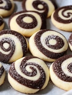 chocolate and white swirl cookies in a baking pan with powdered sugar on the top