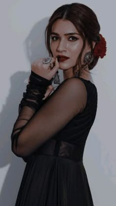 a woman in a black dress posing with her hand on her face