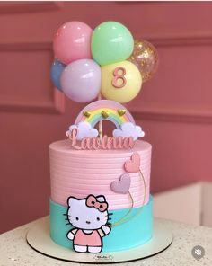 a hello kitty birthday cake with balloons on top