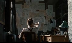 a man sitting in front of a wall covered with papers