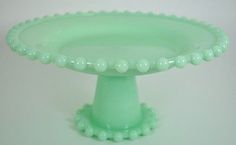 a green glass cake plate with beaded edges