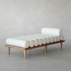 a white couch sitting on top of a wooden frame in front of a gray wall