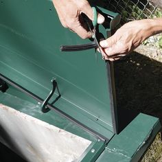 a man is holding scissors in his hand near a green box with wire attached to it