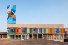 the building is made out of multicolored wood and has a large mural on it's side