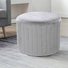 a white round ottoman sitting on top of a rug next to a gray couch and chair