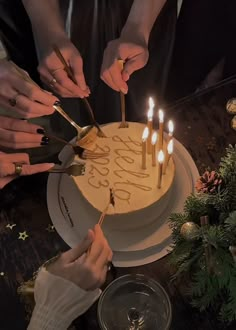 two people cutting into a birthday cake with candles