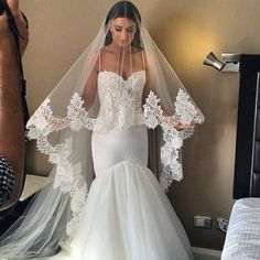 a woman in a wedding dress is taking a selfie with her phone and wearing a veil