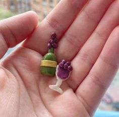 a hand holding a tiny green and purple object